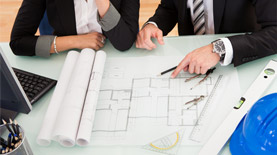 Man and woman looking at blueprints on desk